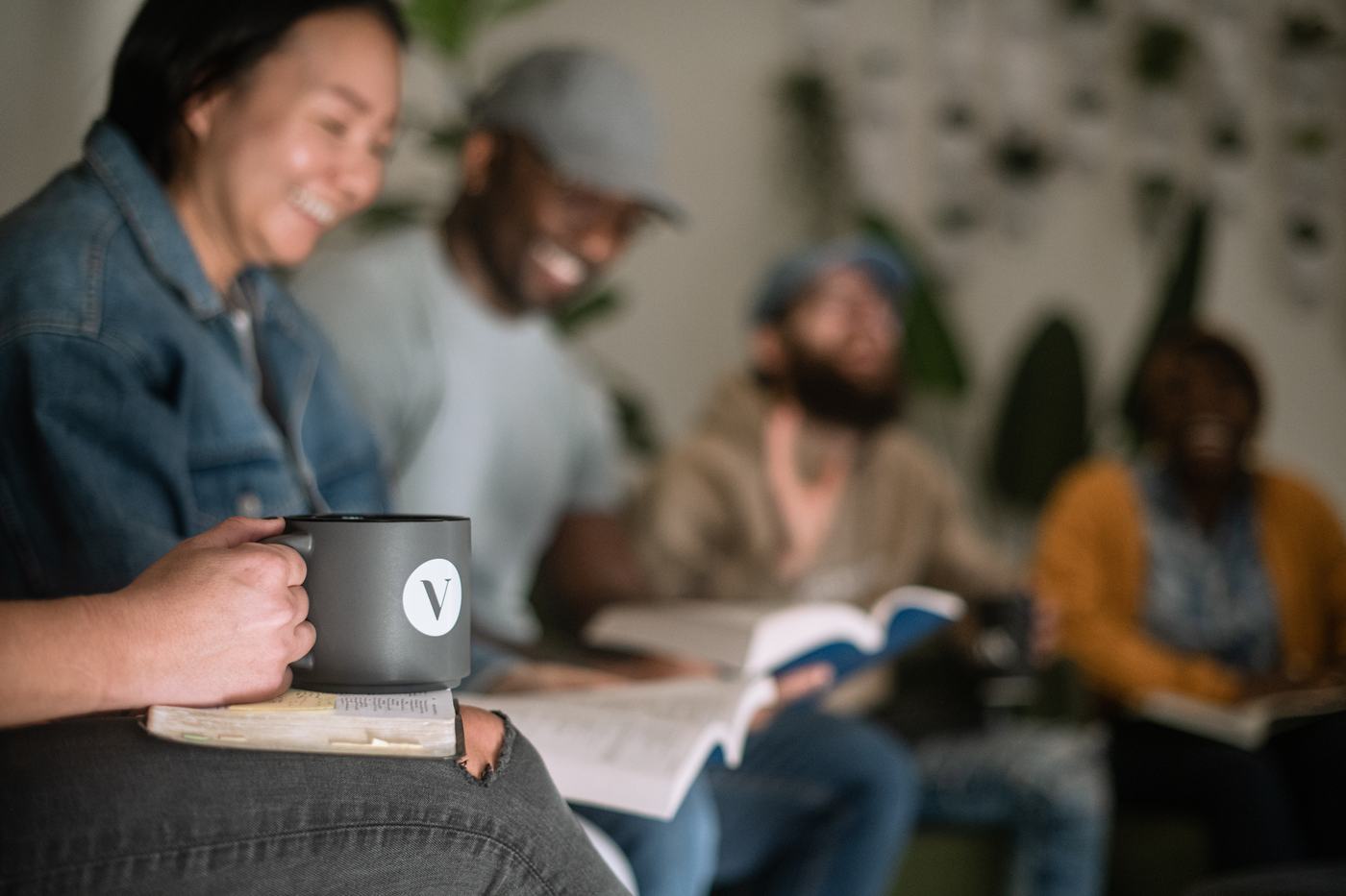 A group member holding a Vox mug resting on a well-worn Bible